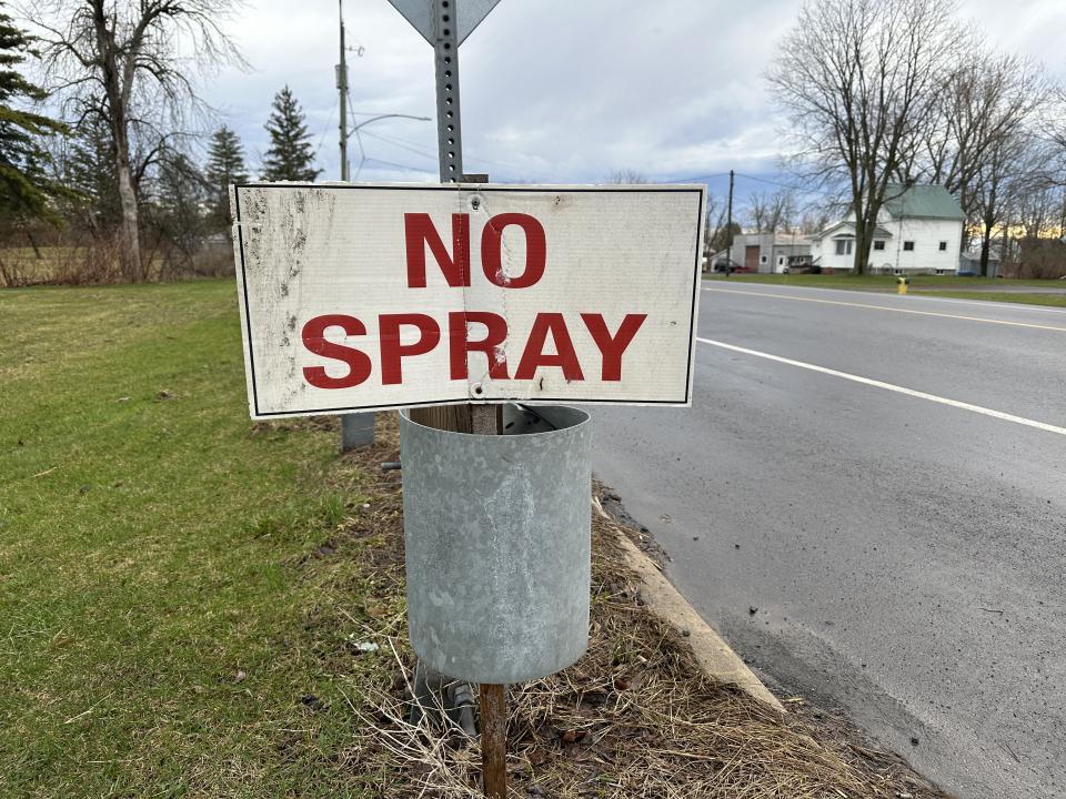 A picture of a road sign with a no spray message on it in red