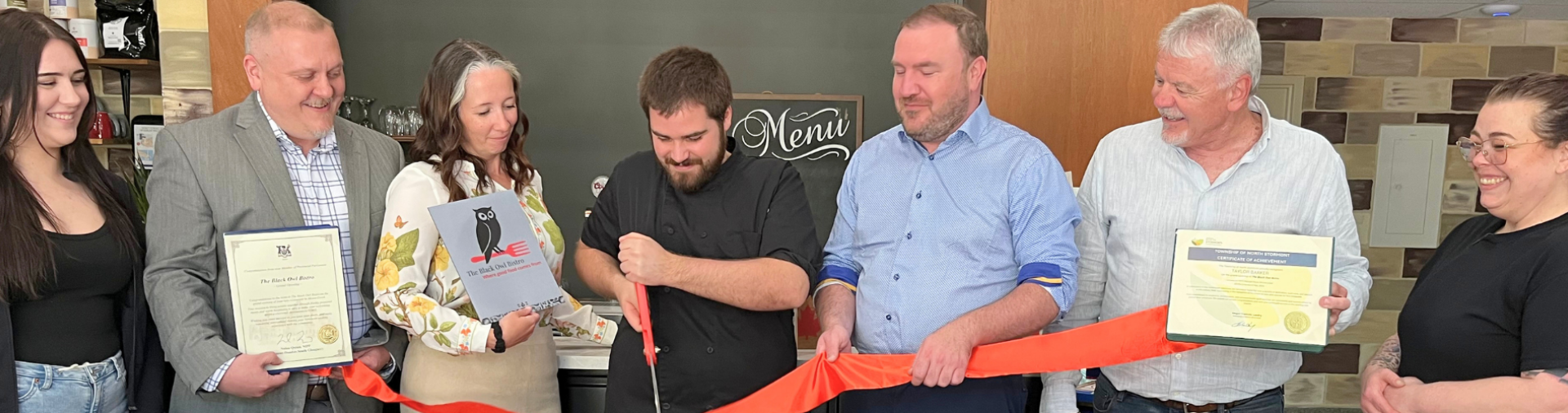 An image of a group of people cutting a red ribbon to open a business