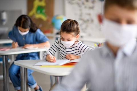 Masked students writing while in the classroom